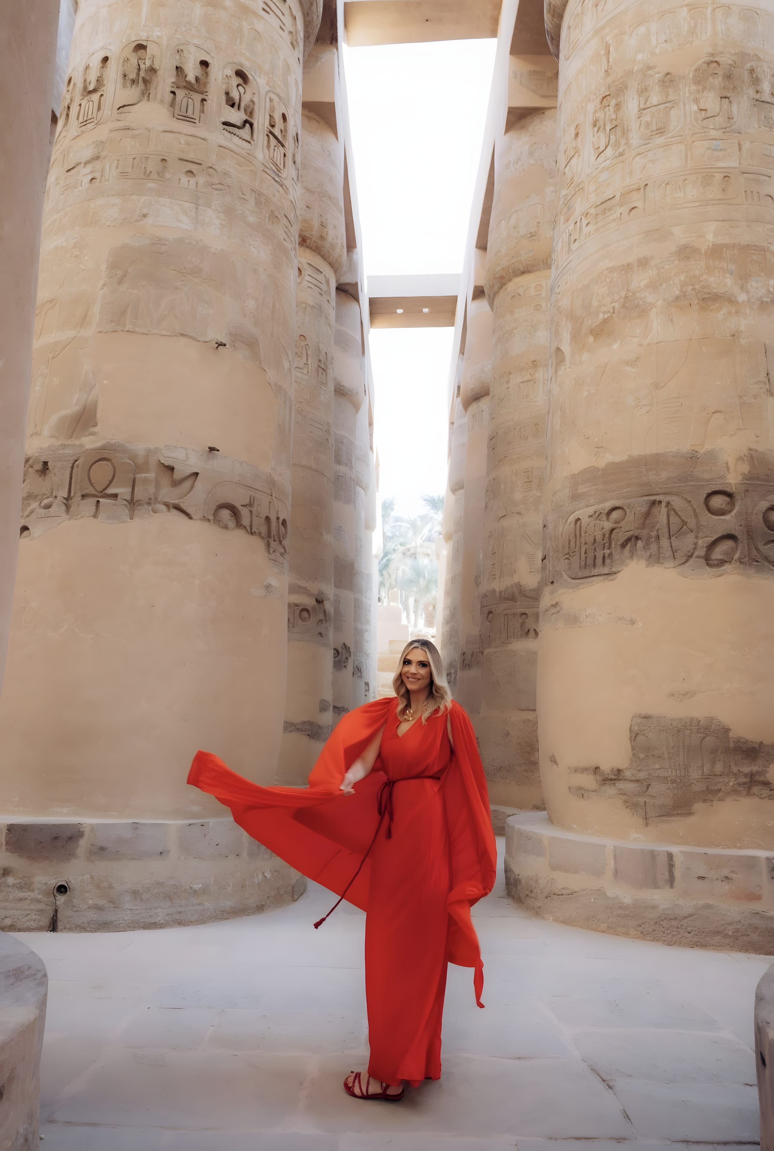 Alexandra in a flowing red dress between the towering carved columns of Karnak Temple