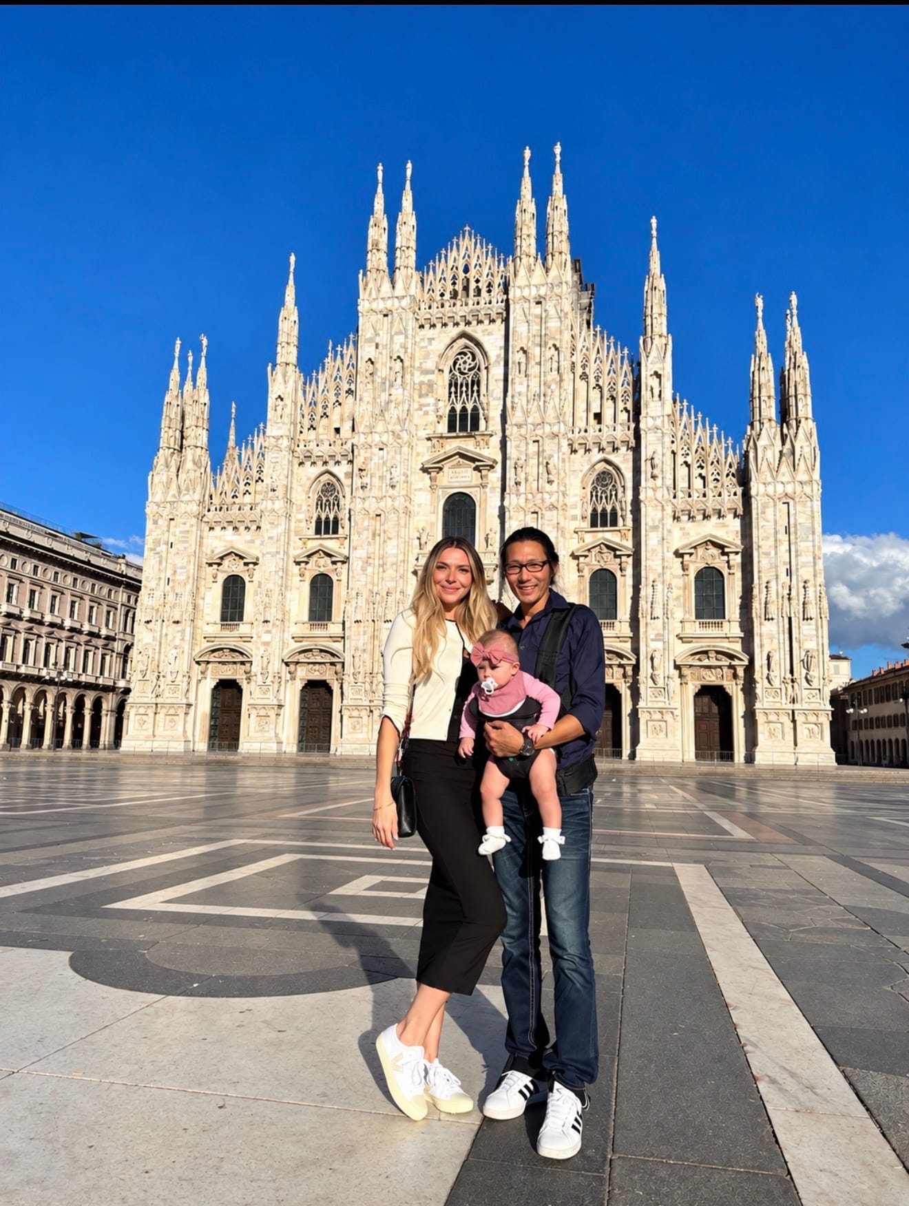 Alexandra and her family with their baby in front of the Milan Cathedral